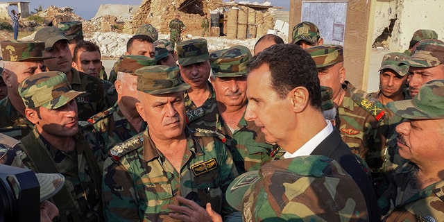 In this photo released on the official Facebook page of the Syrian Presidency, Syrian President Bashar Assad, center right, speaks with Syrian troops during his visit to the town of Habeet, in the northwestern province of Idlib, Syria, on Tuesday. (AP/Facebook page of the Syrian Presidency)