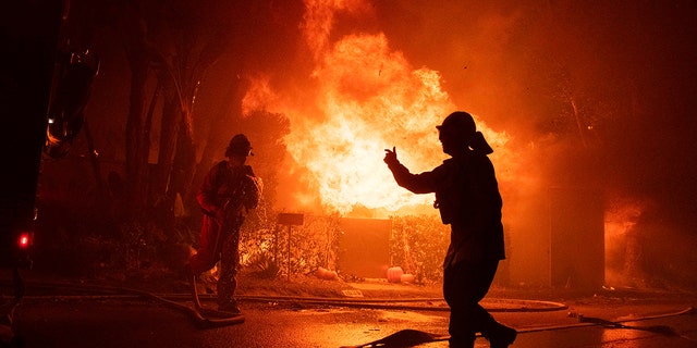 Firefighters try to save a home on Tigertail Road during the Getty fire, Monday, Oct. 28, 2019, in Los Angeles, Calif.