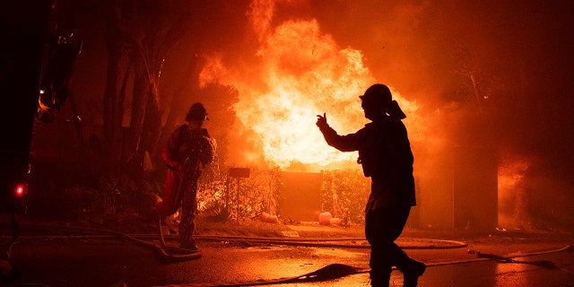 Firefighters try to save a home on Tigertail Road during the Getty fire, Monday, Oct. 28, 2019, in Los Angeles, Calif.