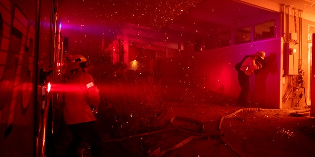 Firefighters try to save a home on Tigertail Road from a wildfire, Monday, Oct. 28, 2019, in Los Angeles, Calif.