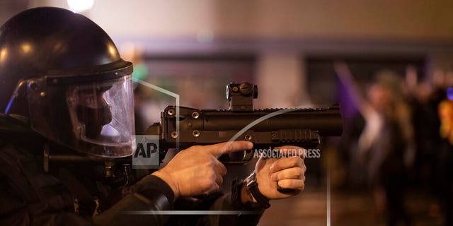 A Catalan police officer aims his weapon against demonstrators during clashes in Barcelona, Spain, Saturday, Oct. 26, 2019. (AP Photo/Emilio Morenatti)