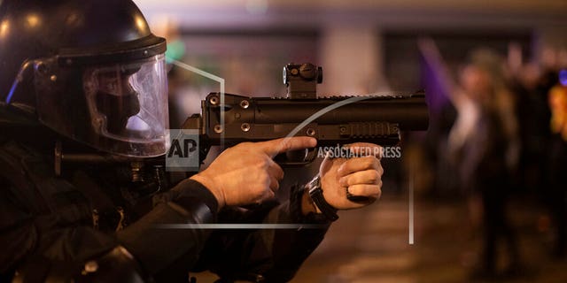 A Catalan police officer aims his weapon against demonstrators during clashes in Barcelona, Spain, Saturday, Oct. 26, 2019. (AP Photo/Emilio Morenatti)