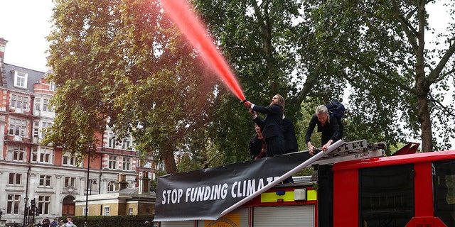 Extinction Rebellion protesters spray a hose outside the Treasury building in London.