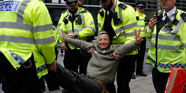 A climate change protester is arrested outside the Home Office in London, Tuesday, Oct. 8, 2019. Police are reporting they have arrested more than 300 people at the start of two weeks of protests as the Extinction Rebellion group attempts to draw attention to global warming. (AP Photo/Alastair Grant)