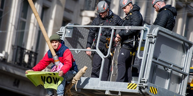 Police work to remove a protester as hundreds of members of the Extinction Rebellion environmental activist group swarm Oxford circus with three activists erecting a road blocking wooden pyramid structure with an upside down tree hanging in the middle on October 18, 2019 in London, England.