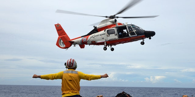 Coast Guard Cutter Munro crew members conduct flight operations with an Air Station Barbers Point HM-65 Dolphin helicopter aircrew from the flight deck on the Munro in the Central Pacific, in December 2018.