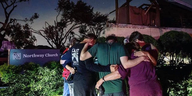 People pray outside Northway Church in Dallas, Texas after a tornado ripped through the community.