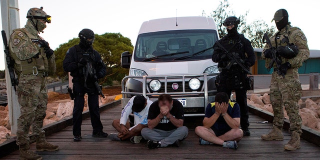 Police officers stand around suspects arrested during an operation that, according to police, resulted in the seizure of 1.2 tons of methamphetamine in Geraldton, Australia, in 2017. (Australian Federal Police/Handout via REUTERS)