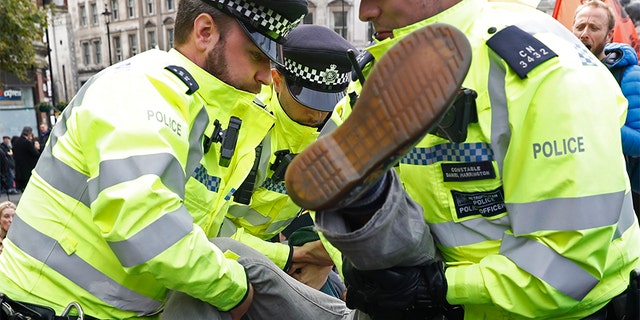Police arrest a climate protestor after demonstrators blocked Trafalgar Square in central London on Monday.