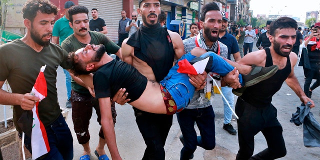 An injured protester being carried after reacting to tear gas fired by security forces during a protest in Tahrir Square, in central Baghdad, last Tuesday. (AP Photo/Khalid Mohammed)