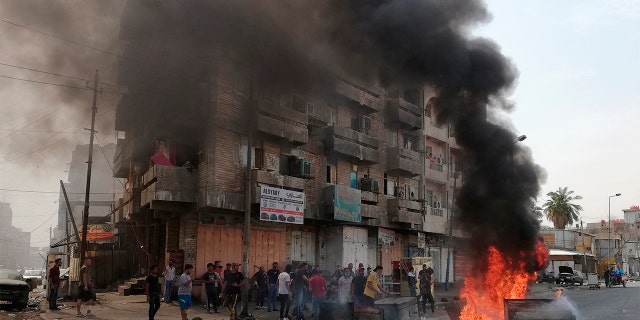 Anti-government protesters setting a fire and blocking roads in Baghdad last Wednesday. (AP Photo/Hadi Mizban)