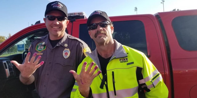This Friday, Oct. 11, 2019, photo released by the North Davis Fire District shows Chief Allen Hadley, left, and Cpt. Kevin Lloyd In Clearfield, Utah. The two Utah firefighters are receiving praise after they found a creative way to keep a young girl calm at the scene of a car accident.