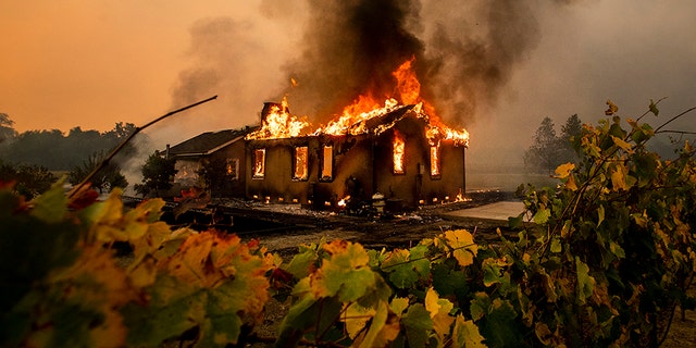 Vines surround a burning building as the Kincade Fire burns through the Jimtown community of unincorporated Sonoma County, Calif., on Thursday. (AP)