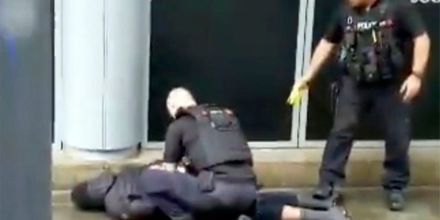 In this image taken from mobile phone footage, police arrest a man outside the Arndale Center in Manchester, England, on Friday, after a stabbing incident that left three people injured.