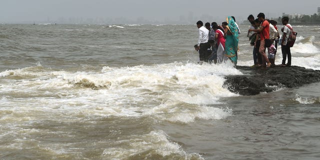 In this photograph taken on September 14, 2019 people gather by the sea during high tide in Mumbai. (PUNIT PARANJPE/AFP/Getty Images)
