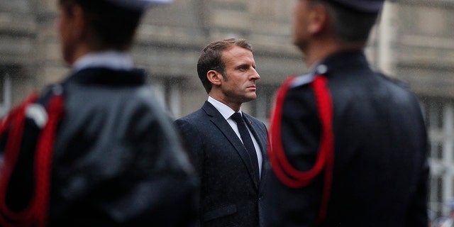 Macron stands at attention by the coffins of the four victims of last week's knife attack in the courtyard of the Paris police headquarters during a ceremony on Tuesday. (AP Photo/Francois Mori, Pool)