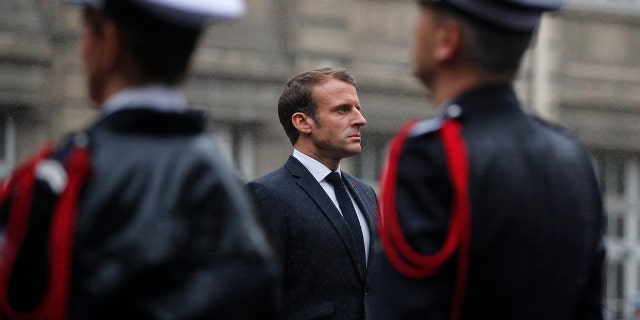 Macron stands at attention by the coffins of the four victims of last week's knife attack in the courtyard of the Paris police headquarters during a ceremony on Tuesday. (AP Photo/Francois Mori, Pool)