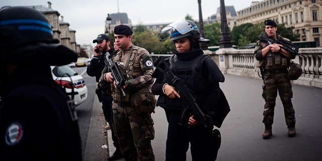 Armed police officers and soldiers patrol after a knife attack at the police headquarters in Paris. (AP Photo/Kamil Zihnioglu)