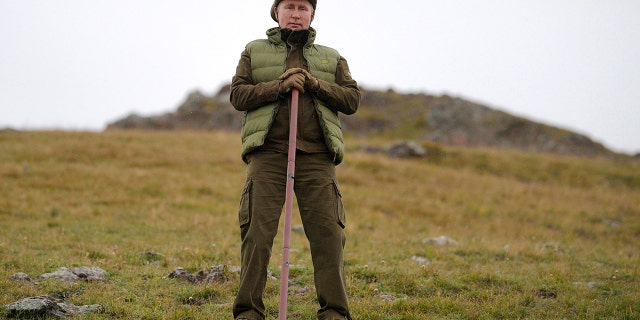 Putin poses with his walking stick on a hill in the Siberian mountains. (Alexei Druzhinin, Sputnik, Kremlin Pool Photo via AP)