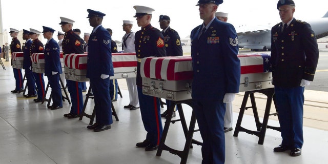 Military members stand at attention after placing transfer cases in a hanger at a ceremony marking the arrival of the remains believed to be of American service members who fell in the Korean War at Joint Base Pearl Harbor-Hickam in Hawaii, in August 2018. (AP)