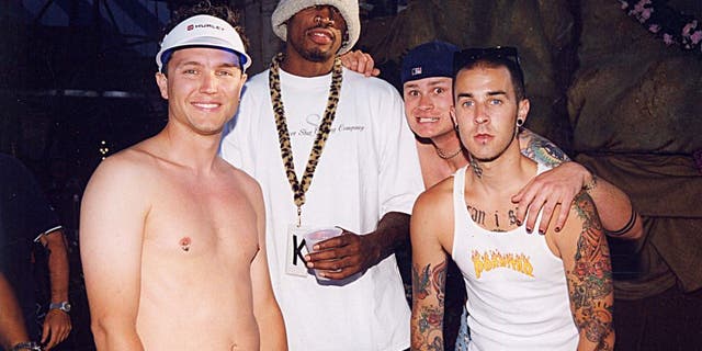 (L to R): Mark Hoppus, Dennis Rodman, Tom DeLonge and Travis Barker at the KROQ Weenie Roast in 1999. (Photo by Jeff Kravitz/FilmMagic, Inc)