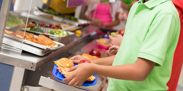 Middle school students getting lunch items in the cafeteria line.