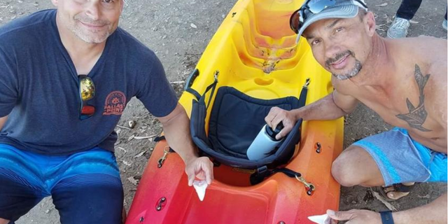 Bill Powers, left, and Danny McDaniel each hold a great white's tooth lost when the shark bit into McDaniel's kayak. <br>