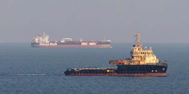 In this image taken from aboard a Royal Navy Wildcat helicopter patrolling the Gulf as part of the International Maritime Security Construct, shows the MV Stena Impero, background, as it sails from the port at Bandar Abbas, Iran, after being released by Iranian officials Friday Sept. 27, 2019. (Dan Rosenbaum/British Royal Navy via AP)