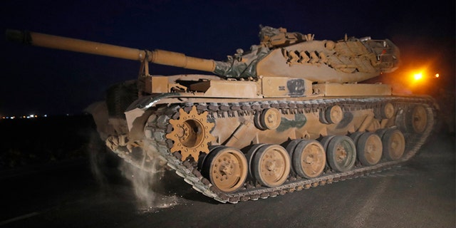 A Turkish army tank is driven to its new position, after was uploaded from a truck, on the Turkish side of the border between Turkey and Syria, in Sanliurfa province, on Tuesday.