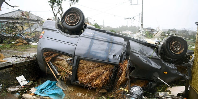 An overturned car lies on the ground following a strong wind in Ichihara, Chiba, near Tokyo Saturday, Oct. 12, 2019. Under gloomy skies, a tornado ripped through Chiba on Saturday.(Kyodo News via AP)