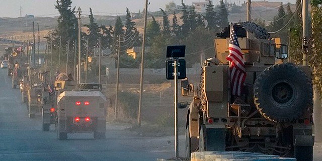 In this image provided by Hawar News Agency, U.S. military vehicles travel down a main road in northeast Syria on Monday.