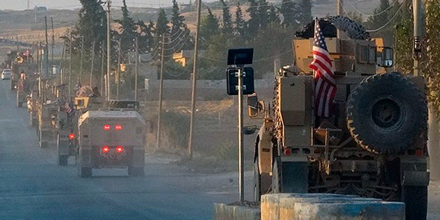 In this image provided by Hawar News Agency, U.S. military vehicles travel down a main road in northeast Syria on Monday.