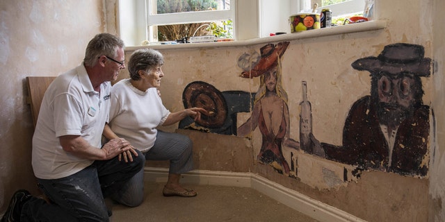 David Parton a staff member at Stokeleigh Care Home who discovered a series of paintings believed to date back to World War II shows them to Jan, a resident at the Care Home. Due to the picture's