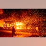 A firefighter passes a burning home as the Hillside fire burns in San Bernardino, Calif., Oct. 31, 2019. 