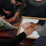 Relatives touch the coffin and photo of police officer Pablo Sergio Reynel, one of a group of officers killed in the line of duty, during a memorial service at the public security department headquarters for Michoacan, in Morelia, Mexico, Oct. 15, 2019. 