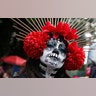 A woman dressed as Catrinas poses for a photo as she joins a parade on Mexico City's iconic Reforma Avenue during celebrations for the Day of the Dead in Mexico City, Oct. 26, 2019. 
