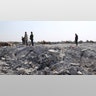 People look at a destroyed houses near the village of Barisha. (AP Photo/Ghaith Alsayed)
