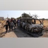 People look at a destroyed van near the village of Barisha. (AP Photo/ Ghaith Alsayed)