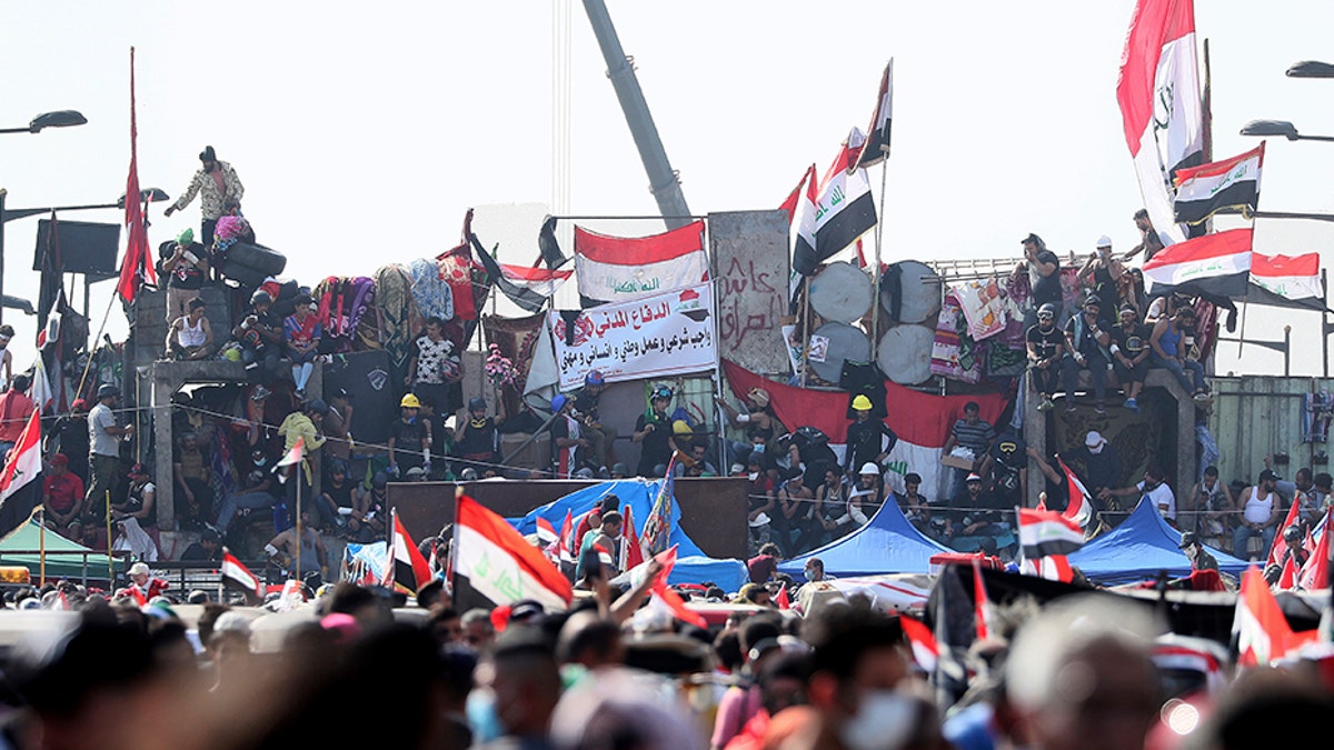 Anti-government protesters stand on barriers set by Iraqi security forces to close a bridge leading to the Green Zone government areas during ongoing protests in Baghdad, Iraq, on Monday.
