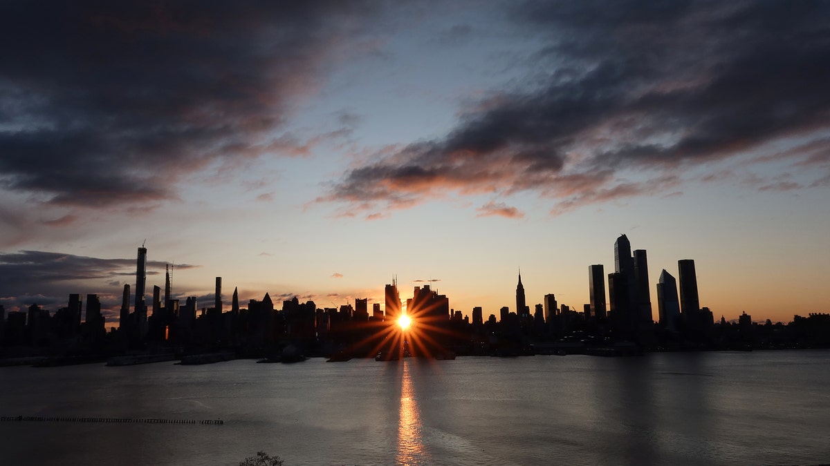The sun rises down 42nd Street behind the skyline of midtown Manhattan and the Empire State Building in New York City on November 28, 2019 as seen from Weehawken, New Jersey.