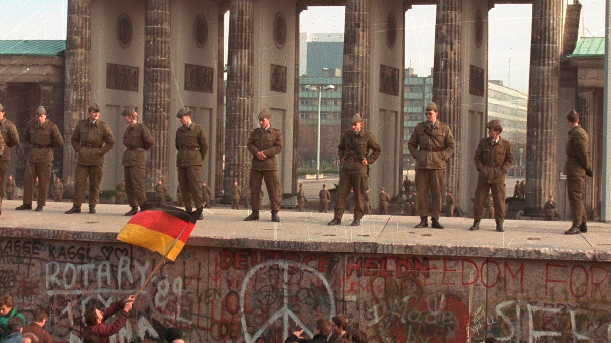 East German border guards standing on top of the Berlin wall in front of the Brandenburg Gate on Nov. 11, 1989. (AP Photo/Lionel Cironneau, File)