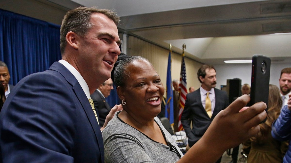 Oklahoma Gov. Kevin Stitt, left, poses for a selfie with Joy Block, right, of Tulsa, Okla., following a news conference Friday to announce that Oklahoma will release more than 400 inmates after the board approved what they say is the largest single-day mass commutation in U.S. history. (AP Photo/Sue Ogrocki)
