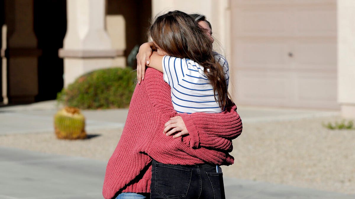 Madelyn Staddon, right, a relative of some of the members of a Mormon community who were attacked while traveling near the US-Mexico border, embraces a neighbor outside her home, Tuesday, Nov. 5, 2019, in Queen Creek, Ariz. Drug cartel gunmen ambushed three vehicles along a road near the state border of Chihuahua and Sonora on Monday, slaughtering at least six children and three women. (AP Photo/Matt York)
