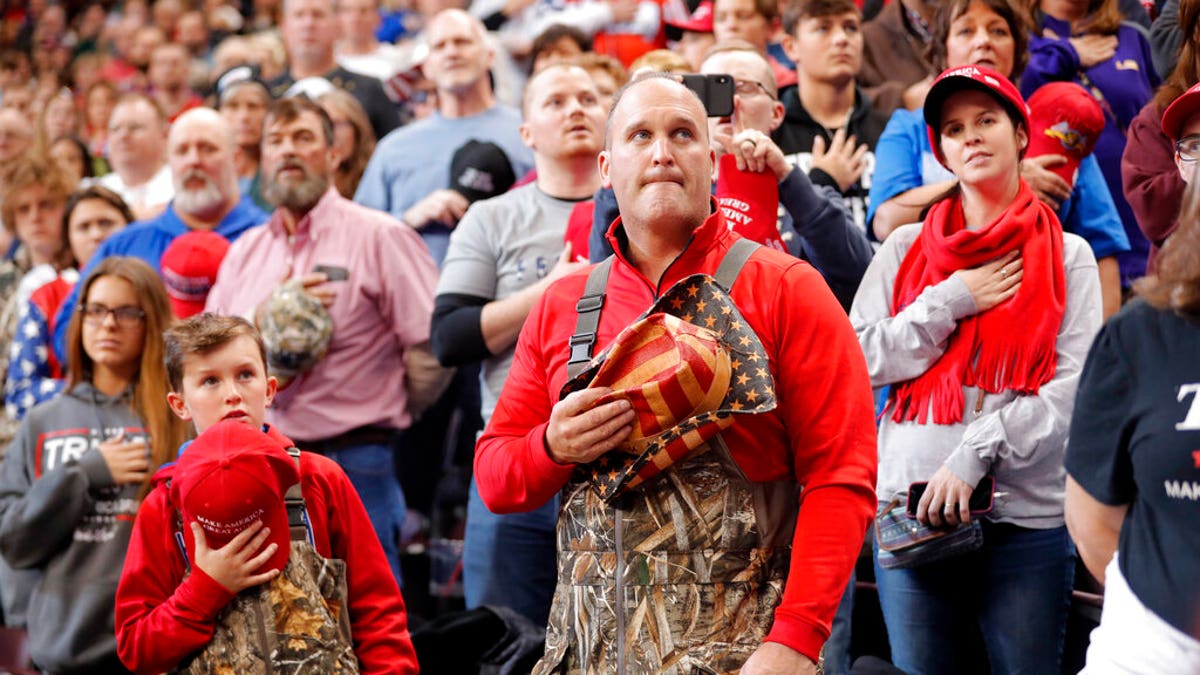 A man and boy dressed in chest waders holding their hats to their hearts during the Pledge of Allegiance at the start of the rally Thursday. (AP Photo/Gerald Herbert)