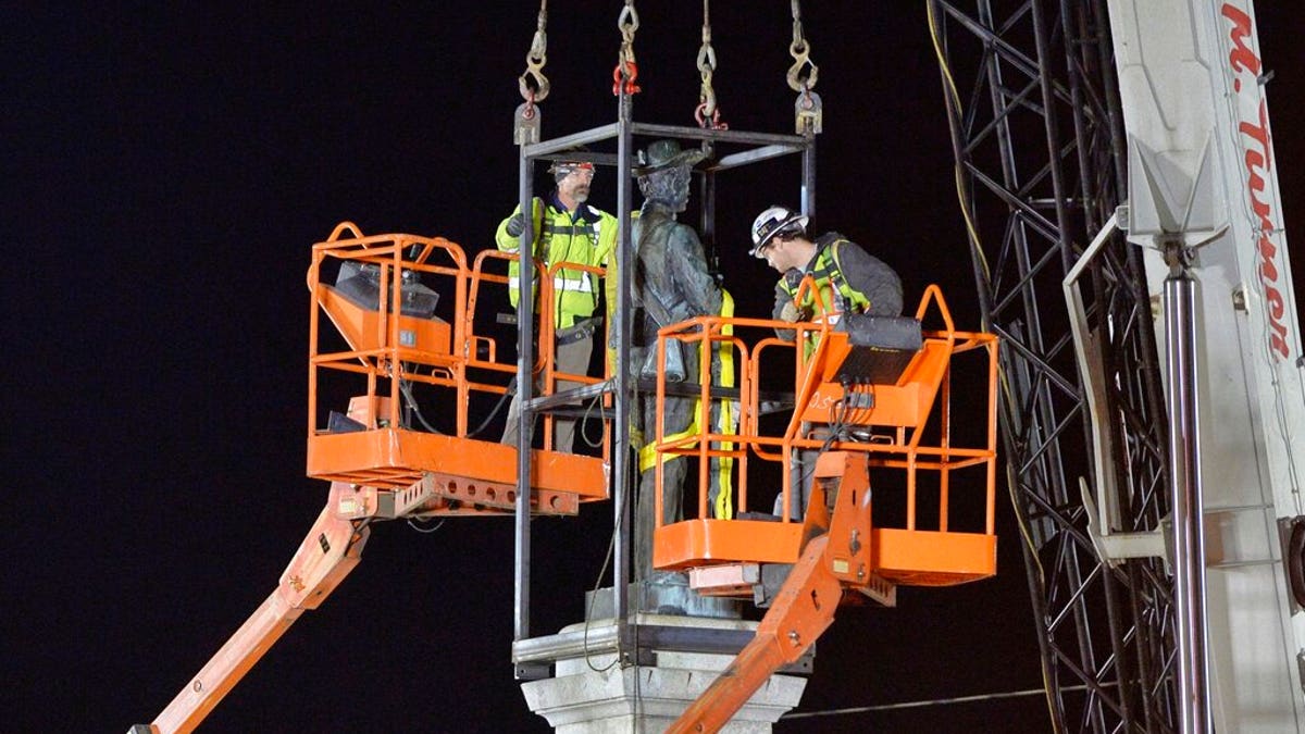 Workers prepare to remove a Confederate statue from its granite pedestal by the Chatham County courthouse in Pittsboro, N.C.