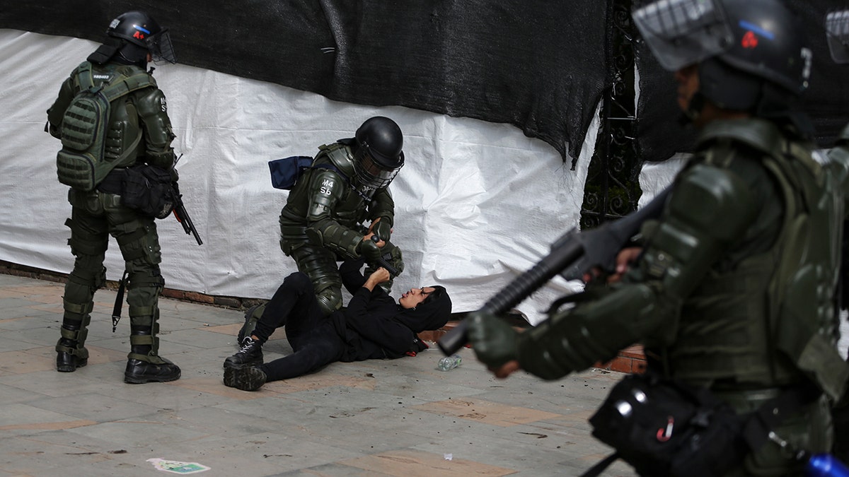 Riot police detain an anti-government protester in Bogota, Colombia, Saturday, Nov. 23, 2019. Authorities in Colombia are maintaining heightened police and military presence in the nation's capital following two days of unrest. (AP Photo/Ivan Valencia)