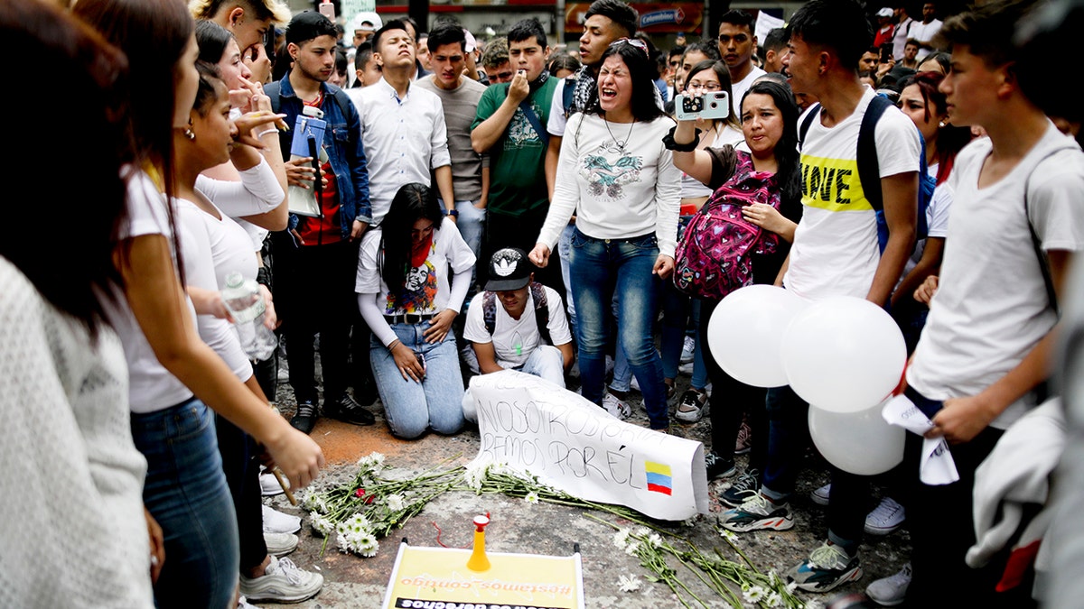 Youth attend a vigil for Dilan Cruz, who was injured during clashes between anti-government protesters and police, in Bogota, Colombia, Sunday, Nov. 24, 2019. President Ivan Duque said he was ordering an urgent investigation to determine who was responsible for the injuries of the 18-year-old student, who is in hospital in critical condition after he was hit in the head Saturday, apparently by a tear gas canister. (AP Photo/Ivan Valencia)