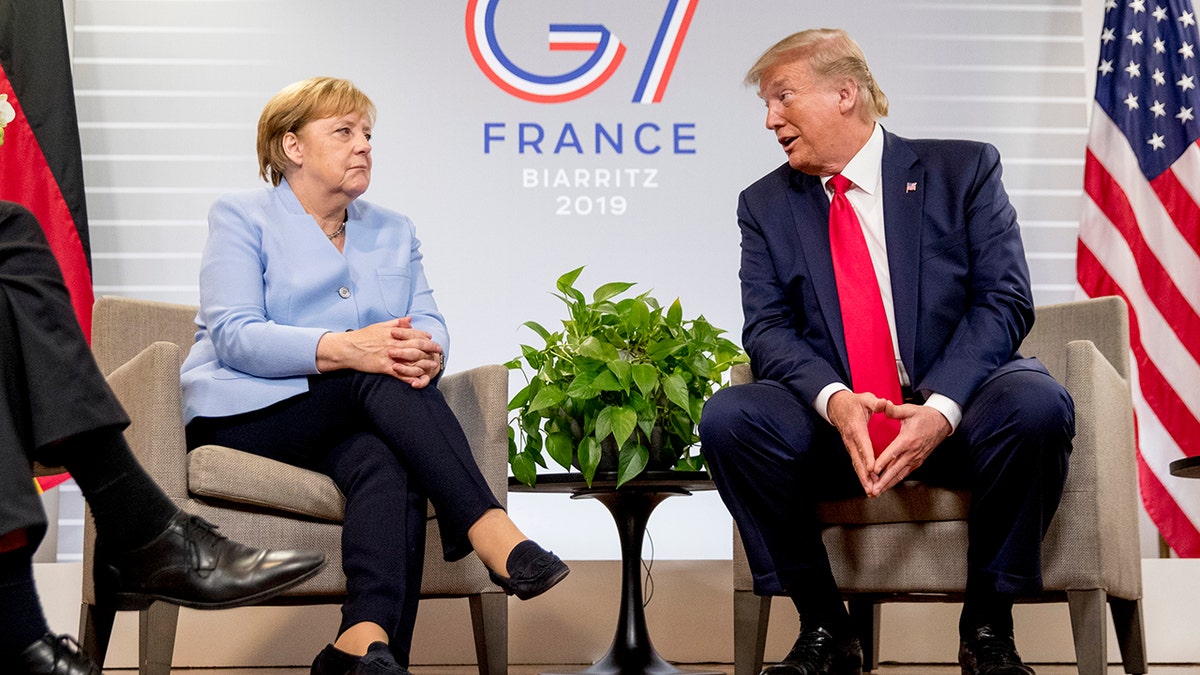FILE - In this Monday, Aug. 26, 2019 file photo, U.S. President Donald Trump, accompanied by German Chancellor Angela Merkel, left, speaks during a bilateral meeting at the G-7 summit in Biarritz, France. (AP Photo/Andrew Harnik)
