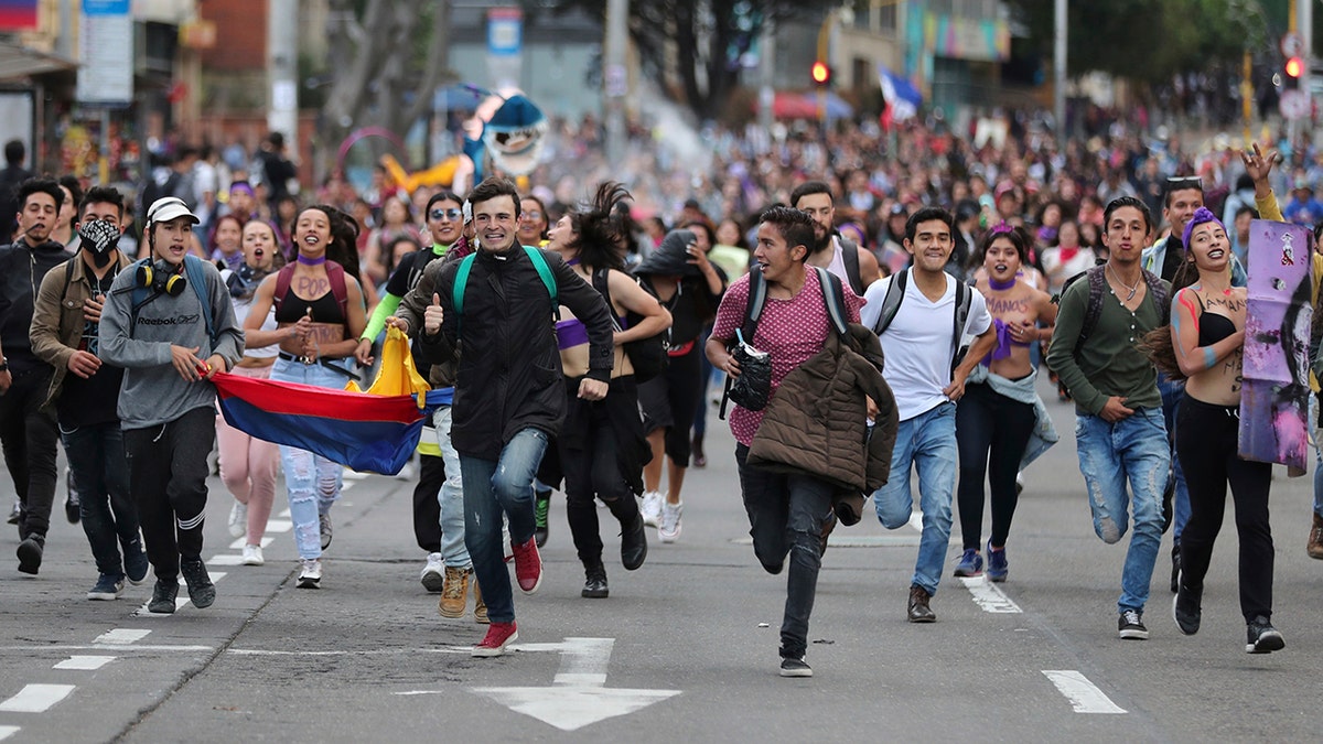 Anti-government demonstrators run during a protest in Bogota, Colombia, Monday, Nov. 25, 2019. Authorities are maintaining a heightened police presence amidst scattered unrest in the aftermath of a mass protest that drew about 250,000 to the streets Thursday. (AP Photo/Fernando Vergara)