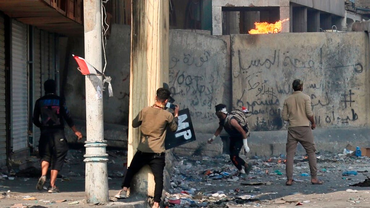 Anti-government protesters throw a Molotov cocktail toward riot police during clashes in Baghdad.